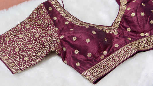 Close up of a traditional brown blouse with intricate gold thread work embroidery
