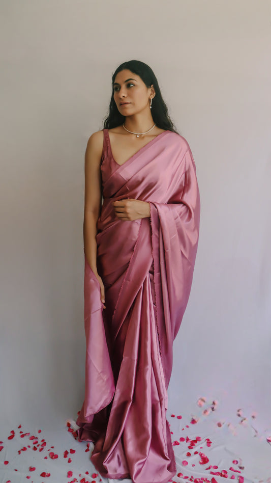 A woman wearing a pink satin saree with mauve undertone