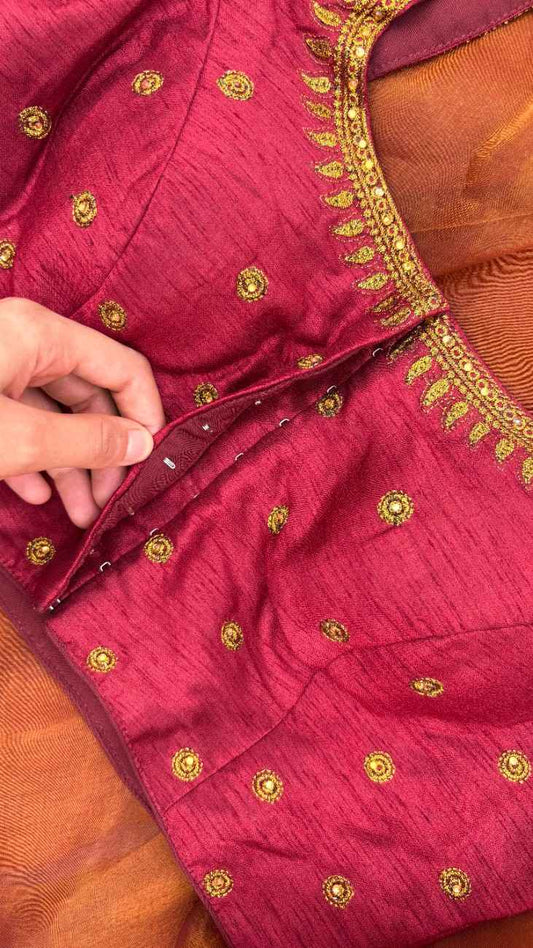 Close-up of Sitara Paisley Blouse sleeve showing hand-done paisley (mango) motifs outlined with gold thread and finished with delicate stone accents. The detailing catches light beautifully, adding a subtle sparkle to the rich maroon silk base