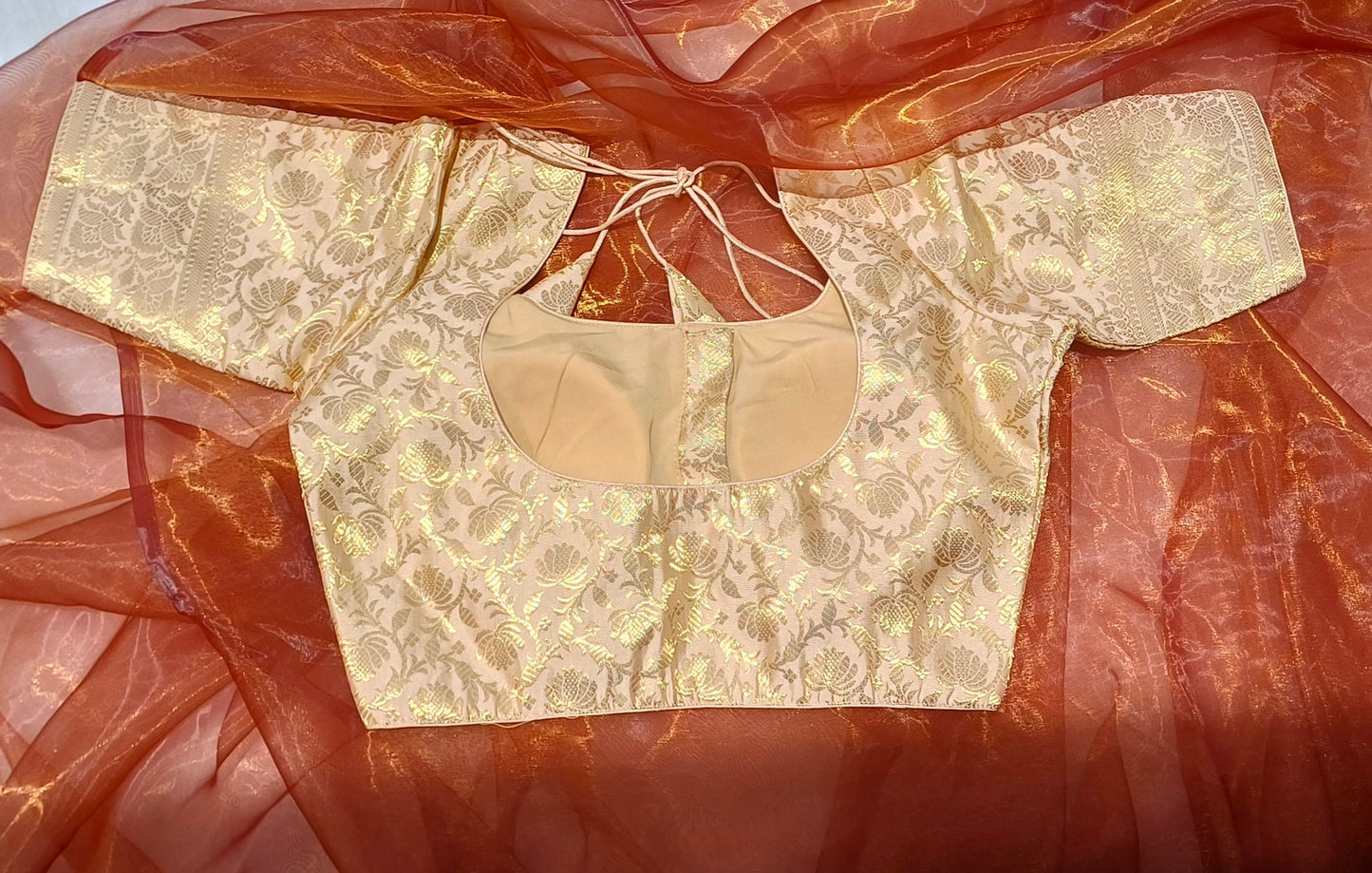 The back of a royal beige blouse paired with a honey organza saree