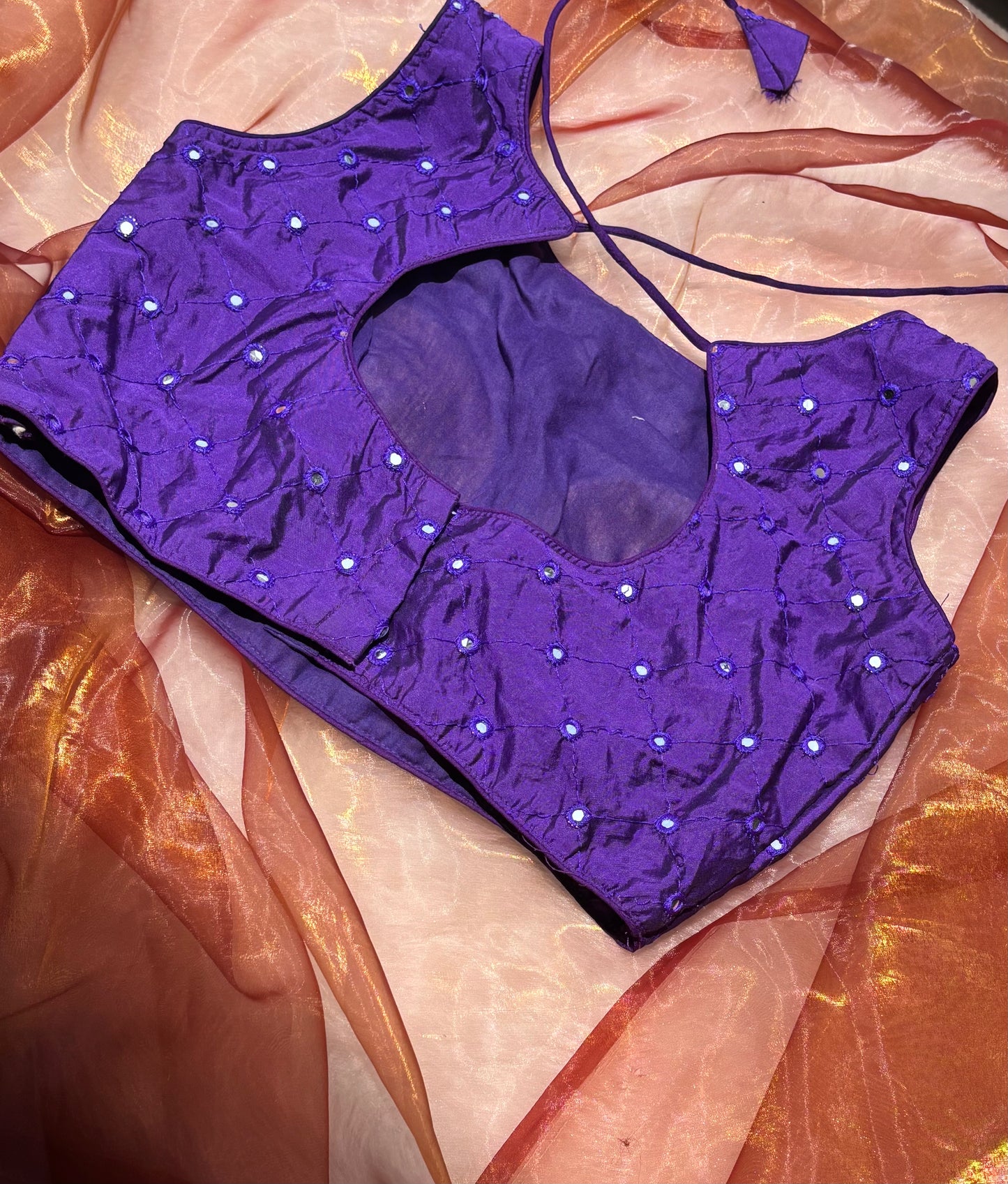 The back of a violet blouse with mirror work