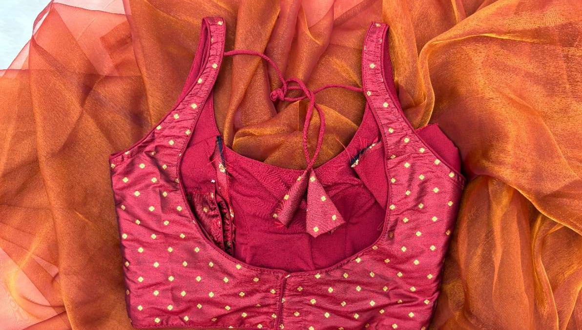 Close-up of maroon silk brocade fabric with gold flower motifs and rich texture – Label Anaira blouse detail