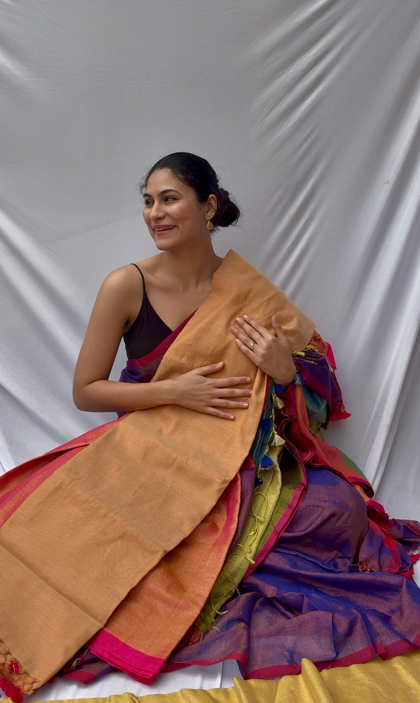 Woman wearing a shining cream pink beautiful saree against a plain background