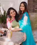 Mom and daughter wearing sarees, blue organza and green linen tissue happily smiling and posing
