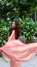 Woman twirling in pink shimmer saree with gold shimmer against greenery — Blushing Bride pink satin silk saree by Label Anaira