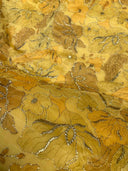 Close-up of a tmarigold aurielle fabric with floral patterns in gold and brown.