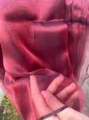Close-up of red fabric with a hand holding it, outdoor background