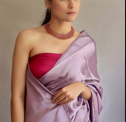 Woman wearing a purple saree with a contrast blouse and necklace against a neutral background