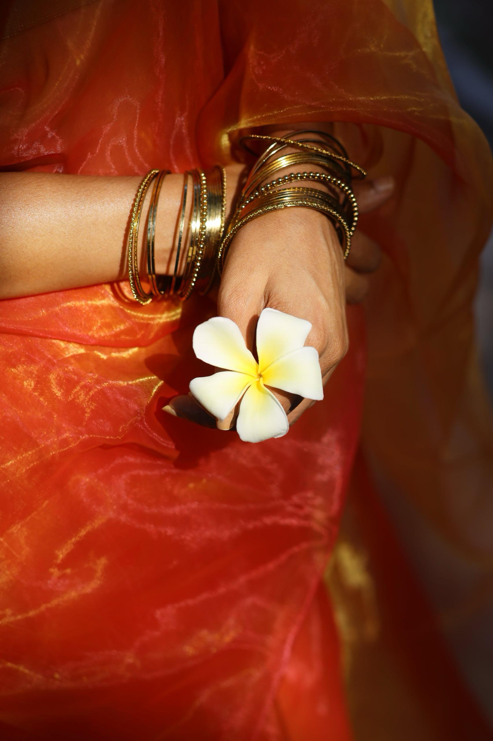 Close up of orange gold organza saree shining under sunlight 