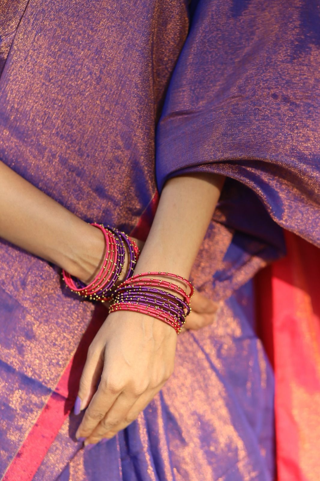 Close up shot of puple cotton tissue with pink pallu shining worn with glass bangles  