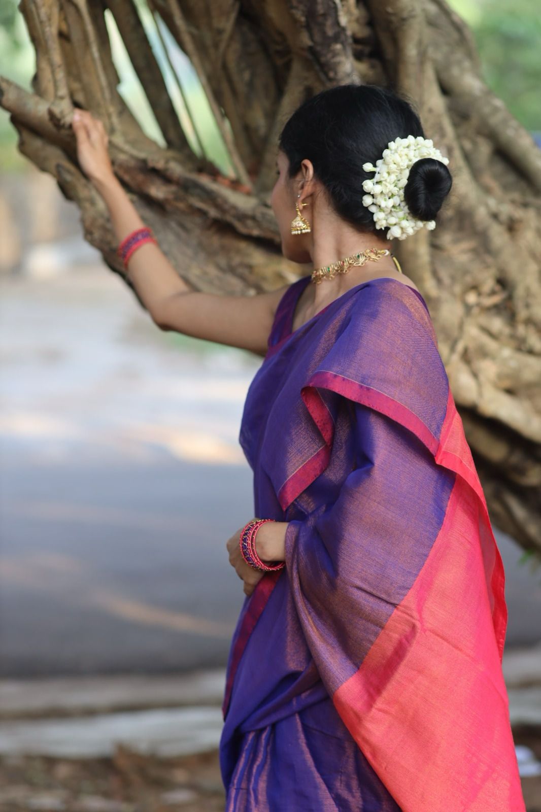 Woman wearing flowers styling Purple cotton tissue saree with pink pallu so gracefully