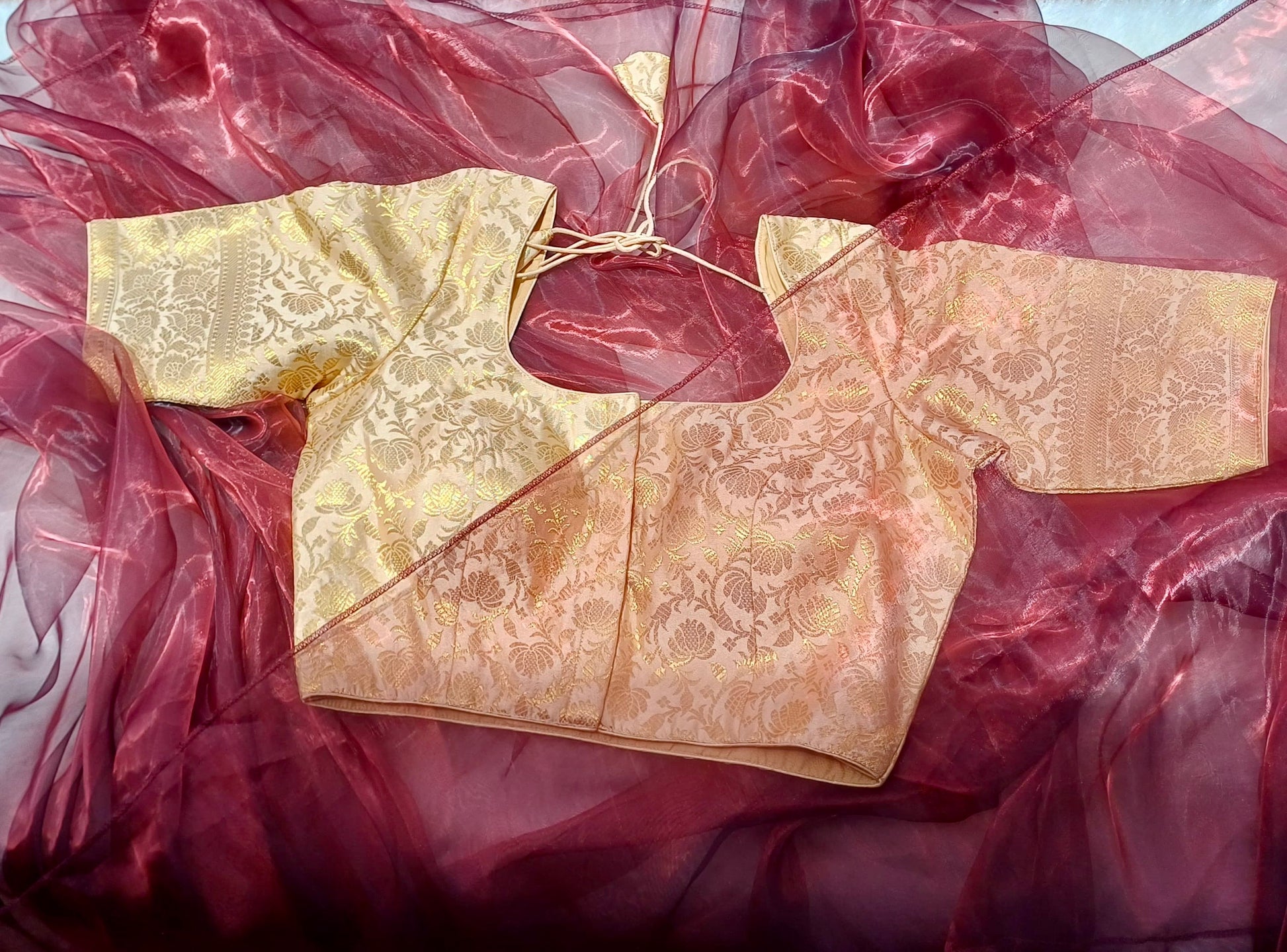 Red organza saree placed over cream gold blouse stunning combination