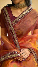 Honey Organza Saree with intricate border and a person sitting