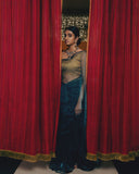 Woman in Dark Blue Organza saree standing behind red curtains