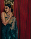 Woman in Dark Blue Organza with gold jewelry against a red curtain