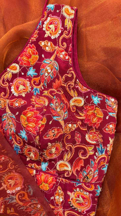 Detailed close-up of the intricate floral embroidery on deep maroon crepe fabric of the Rang Mahal Blouse by Label Anaira, showing vibrant thread work in orange, light blue, and off-white. Perfect for weddings, festive occasions, and saree ensembles