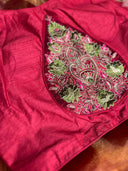 Close-up of a red fabric with green and pink embroidered design