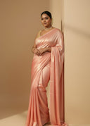 Woman wearing a pink saree against a beige background, the saree is satin silk shimmer, shining under sunlight 