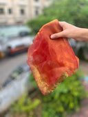 Hand holding a translucent orange fabricwith a blurred outdoor background