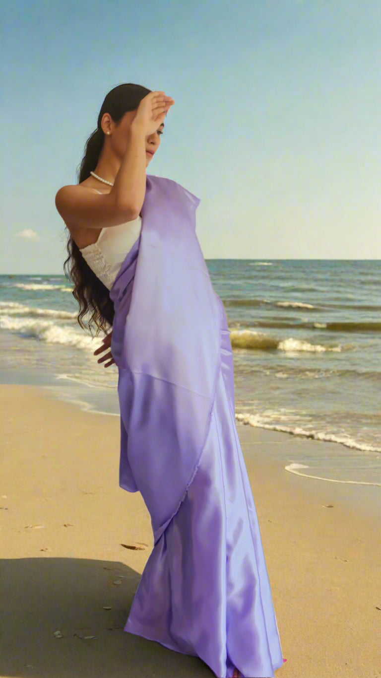a woman wearing a lavender satin saree with a white sleeveless blouse 