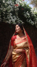 Woman in Molten Gold Tissue Saree standing in front of white flowers