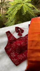 Red outfit with matching earrings on a white surface with greenery in the background