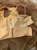 Beige top with embellishments on a sheer brown fabric background