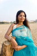 Woman in a blue saree standing on a beach