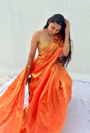 Woman wearing an orange saree with a gold blouse against a white background