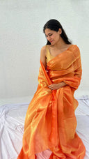 Woman wearing an orange saree against a white background