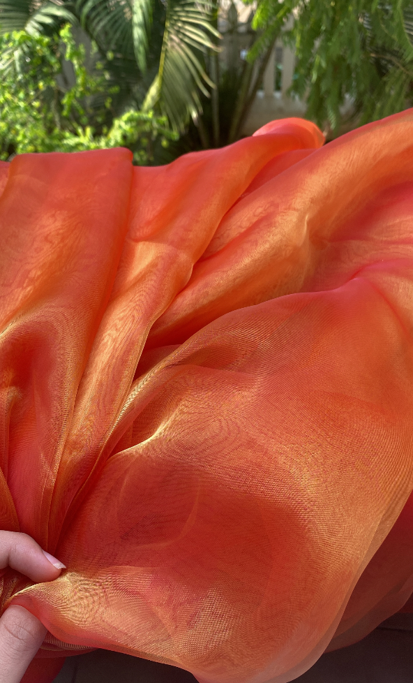 Orange Organza saree shown in close up to highlight the shine and golden glow when under the sun 