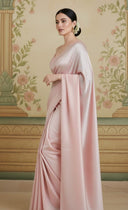 Woman wearing a light pink saree in a festive setting