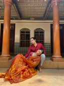 Man and woman in traditional attire sitting on steps in a decorative interior setting.