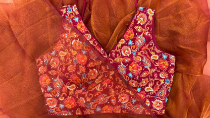 Styled look of the Rang Mahal Blouse paired with a festive honey queen bee saree. Sleeveless maroon crepe blouse with dori tie-up back, rich multicolored floral embroidery, and subtle shine create a luxurious and elegant ensemble for weddings, parties, and traditional celebrations.
