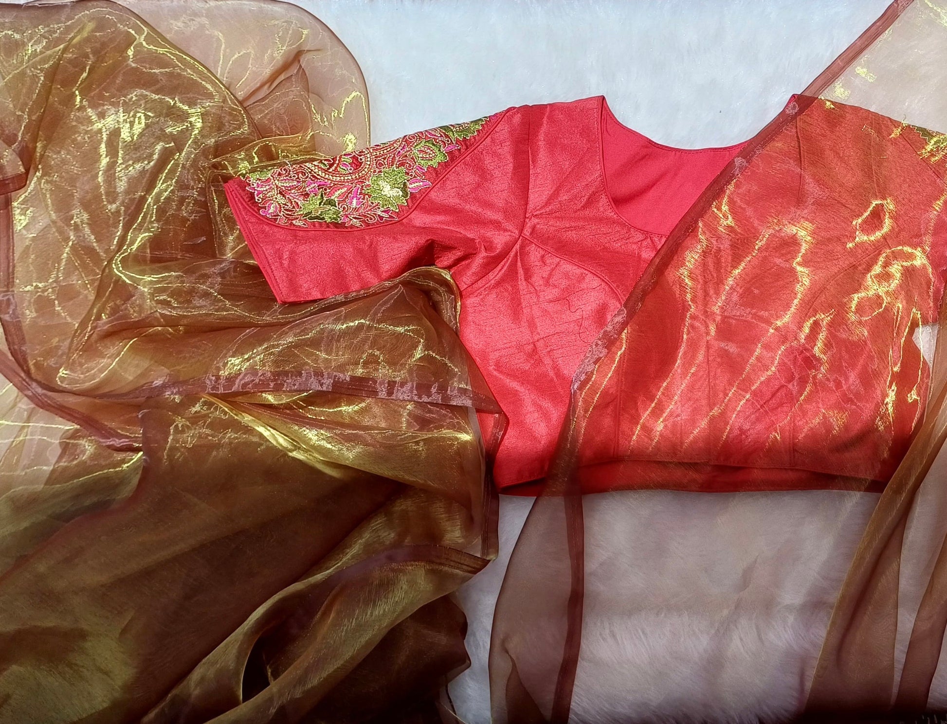 Red blouse with colourful floral zardozi embroidery paired with an amber organza saree