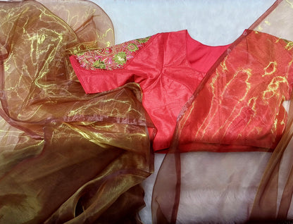 Red blouse with colourful floral zardozi embroidery paired with an amber organza saree