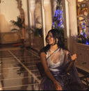 Woman in purple organza saree sitting indoors
