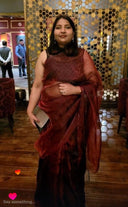 Woman in blood red organza saree against a decorative wall