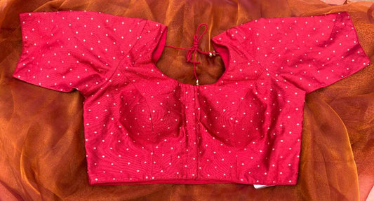 Front view of Label Anaira’s Sindoor Gold Polka Blouse, a rich sindoor red blouse adorned with shimmering gold polka embroidery. Sleeveless design with dori tie-up back, perfect for festive occasions and wedding saree ensembles, highlighting traditional yet contemporary craftsmanship