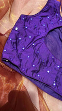 Purple blouse with sequins on a patterned fabric background