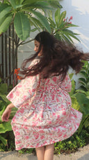 Woman twirling in Summer winds dress with long dark hair in a garden setting