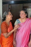 Two women in Sunset : Reversible Sareesarees smiling and interacting indoors.