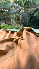 Close-up of Teal green and Mango Reversible Saree with blurred green foliage in the background
