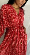 Woman wearing a red patterned dress against a white background