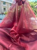 Close-up of Blood Red Organza Saree fabric held up with blurred outdoor background — Label Anaira