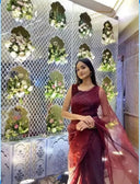 Woman in Blood Red Organza Saree in front of a floral decorated wall — Label Anaira