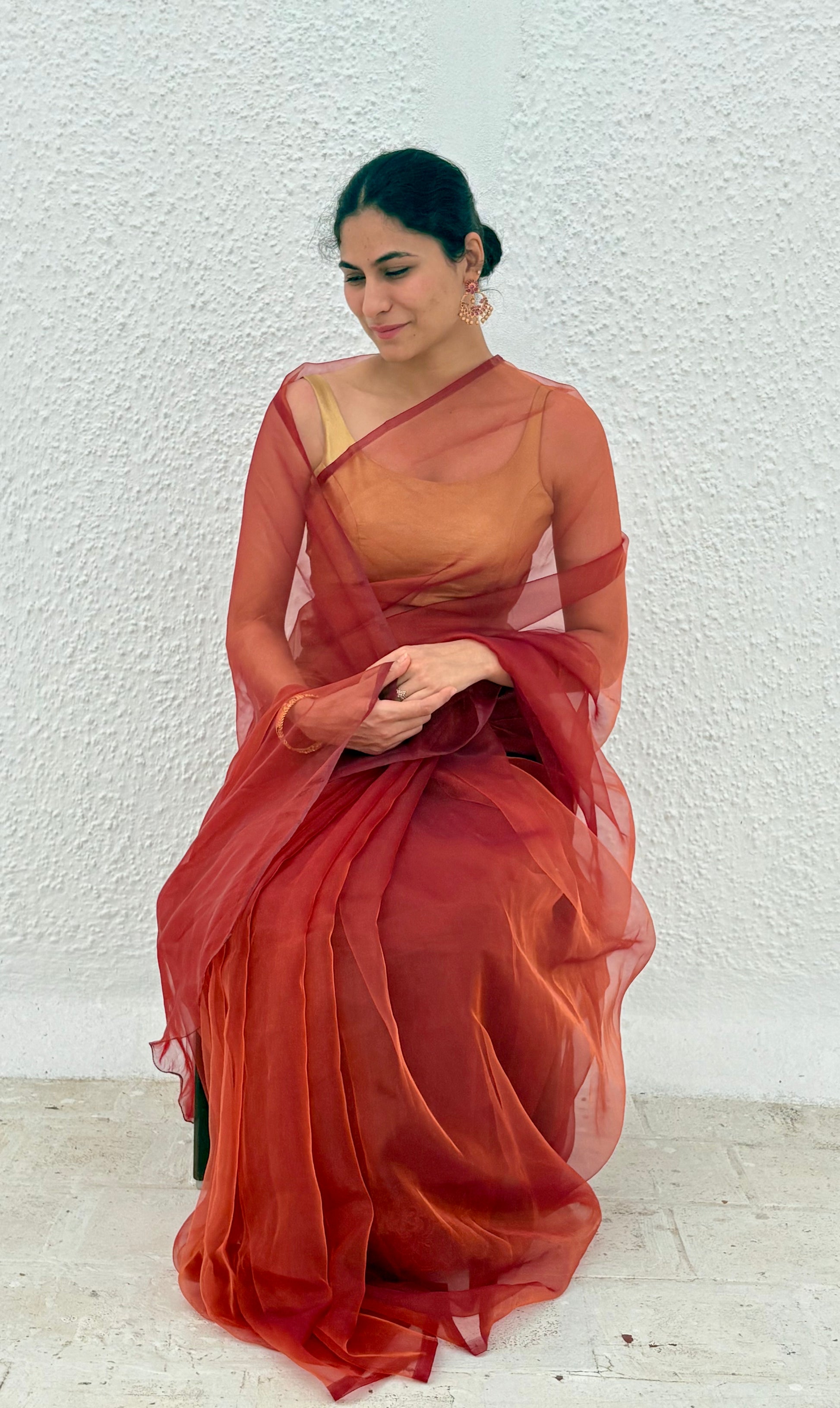 model wearing red maroon orange pink and gold shade organza saree