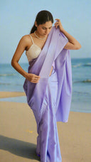 a woman wearing a lavender satin saree with a white blouse