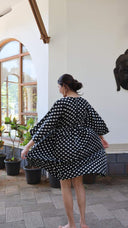 Back view of black polka dot satin dress with relaxed fit