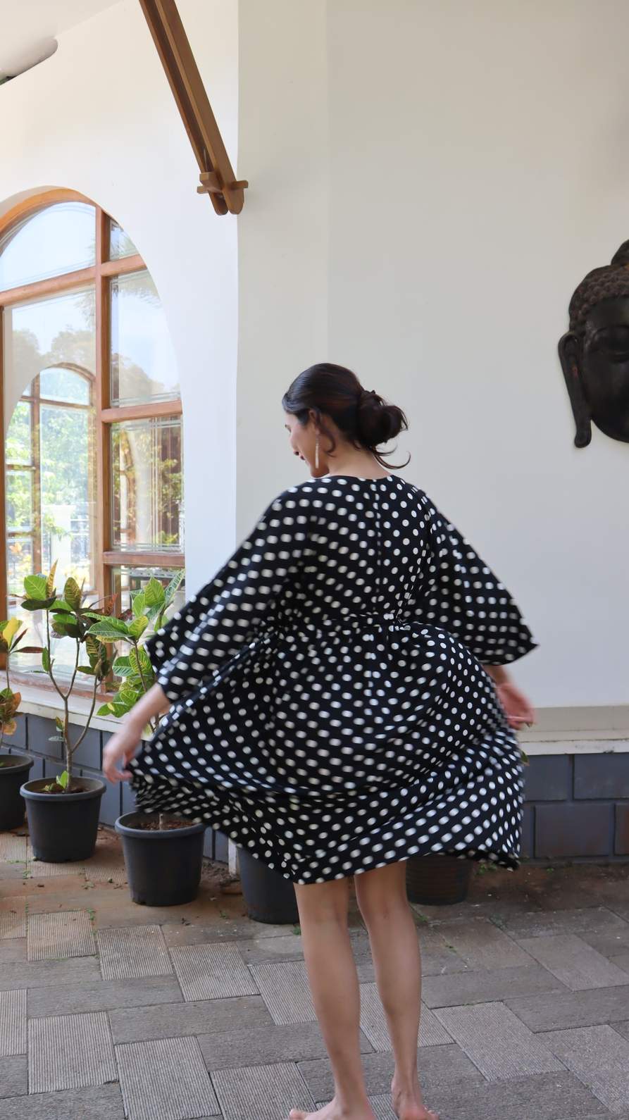 Back view of black polka dot satin dress with relaxed fit